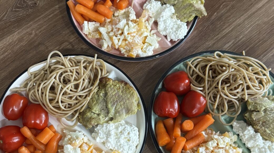 Three portion control plates with a balanced family meal: noodles, cherry tomatoes, carrots and cottage cheese