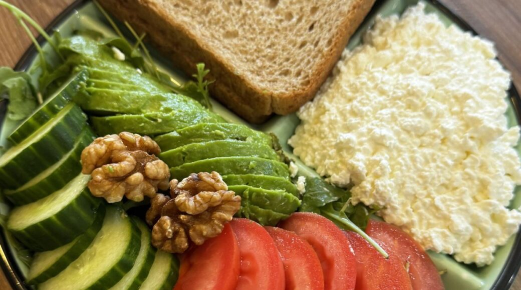 Light lunch: avocado, tomato, cottage cheese, walnuts and wholegrain bread on a portion control plate